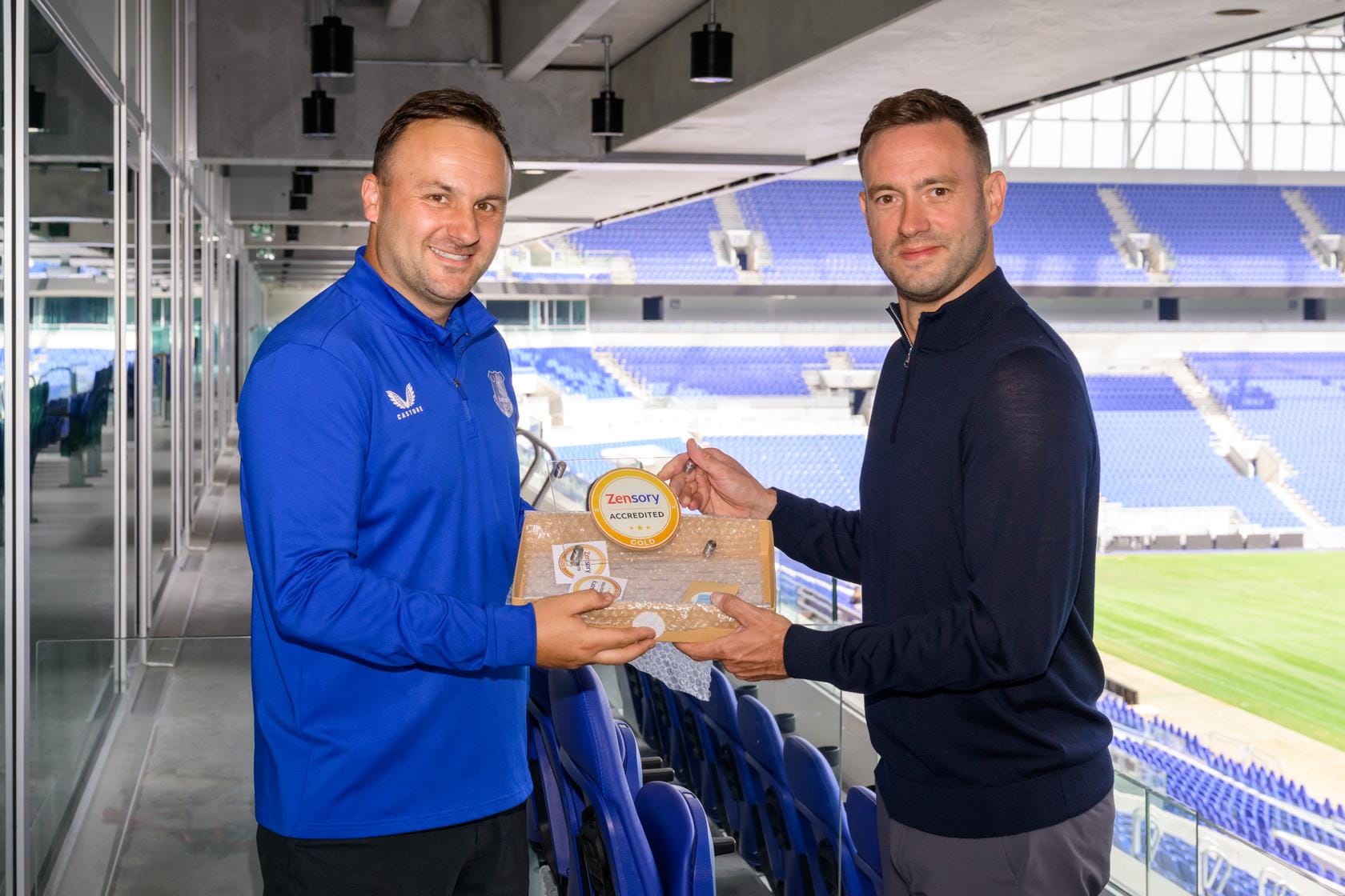 Everton representative and Zensory assessor present the Gold accreditation award inside the stadium
